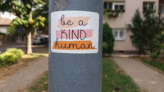 a sticker on a pole that says be a kind of human