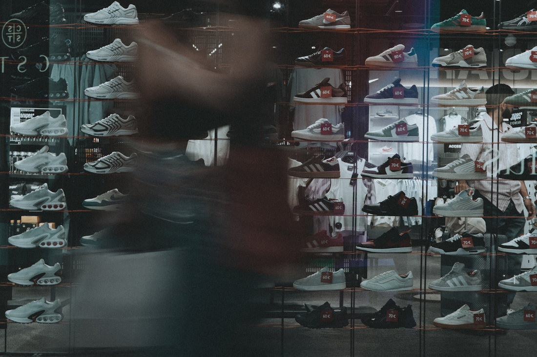 Sneakers displayed inside a shoe store window.