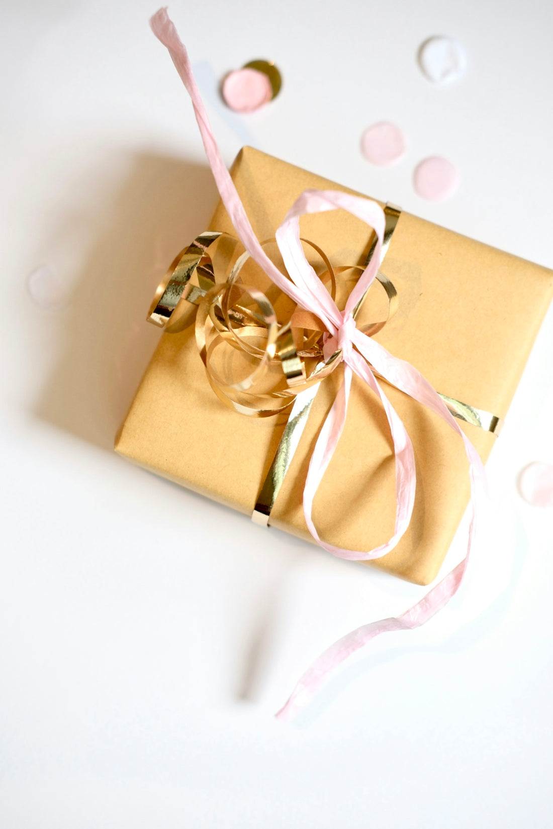 A golden gift box tied with pink and gold ribbons