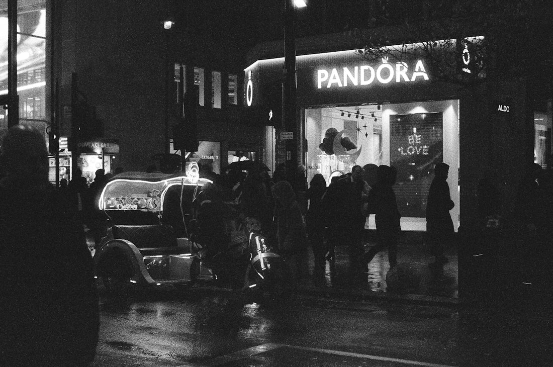 Night street scene with pandora store and vintage car.