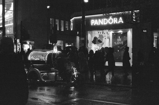 Night street scene with pandora store and vintage car.