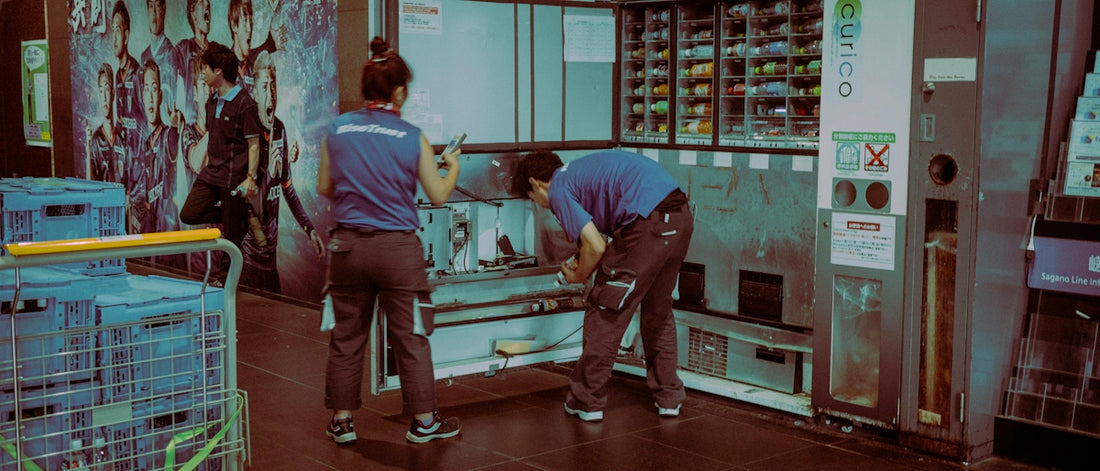 Two workers service a vending machine.